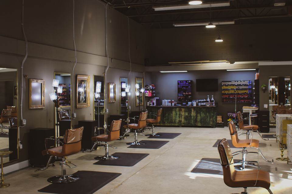 Inside the North Hills studio: styling chairs along a wall of gilt mirrors and ring lights, with the color bar across the back wall.